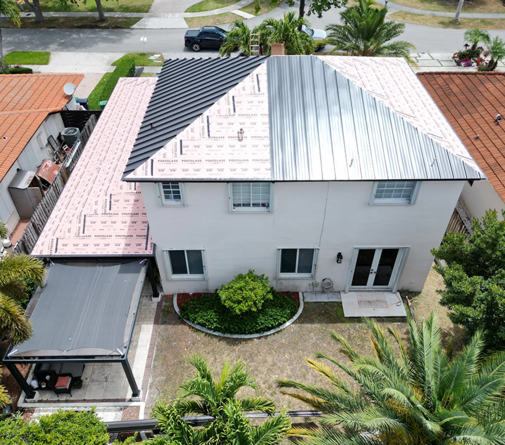 Titan crew mid-install on a standing-seam metal roof — underlayment and panels going down